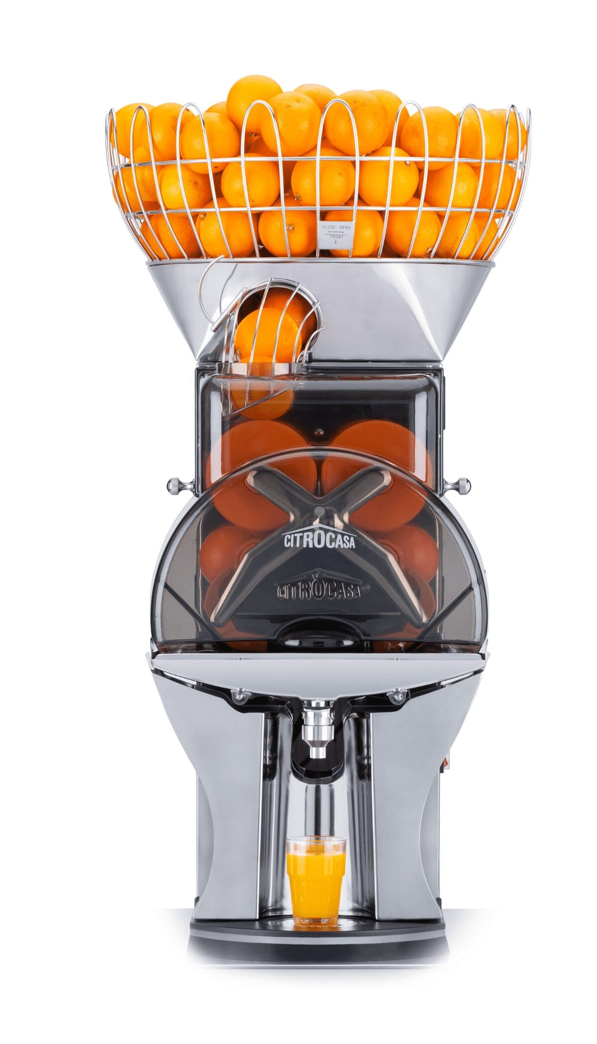 A Citrocasa commercial juicer filled with whole oranges in a basket on top and sections ready for juicing below. The machine is dispensing fresh citrus juice into a glass placed at the bottom outlet. The machine has a sleek, modern design with a metallic finish, embodying the excellence of Citrus America.