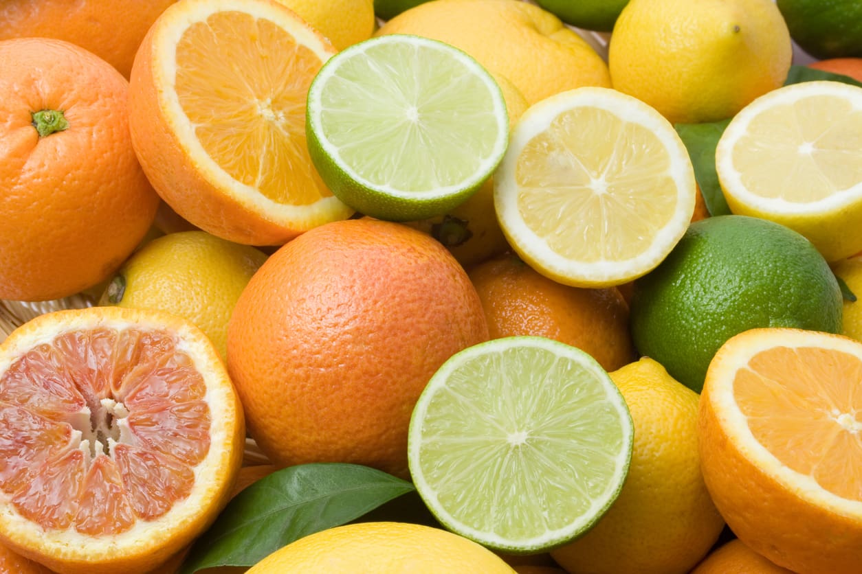 A vibrant assortment of sliced and whole citrus fruits, including oranges, lemons, limes, and grapefruits. The fruit displays a mix of bright orange, yellow, and green hues, showcasing the juicy interiors and textured rinds—the perfect way to store citrus fruit for lasting freshness.