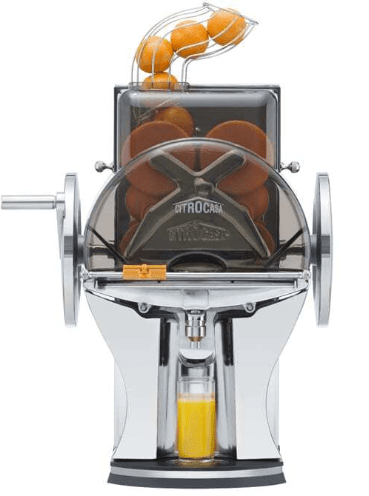 A sleek, modern commercial juicer in chrome finish. The device features a transparent hopper filled with whole citrus at the top and a small bottle collecting freshly squeezed orange juice at the bottom. A hand crank is visible on the left side—a perfect addition to any Citrus America setup.